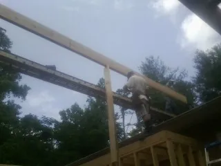 Carpenter setting a ridge beam over a new addition frame — Ice Dam Removal by Roofing Brothers in Lithonia