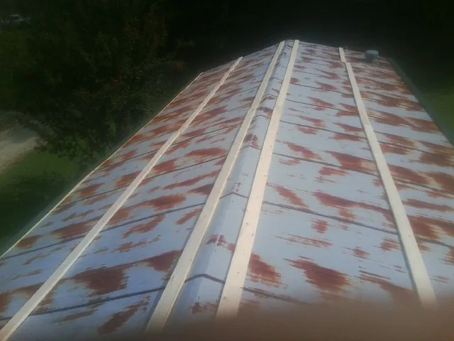 Rusted metal roof panels with new wood purlins before replacement — Storm Damage Roof Repair in Lithonia by Roofing Brothers
