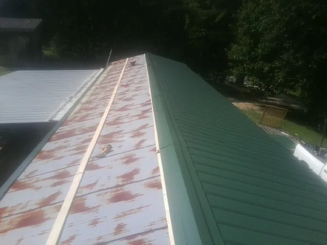 Old rusted panels beside newly installed green metal roofing — Wind Damage Roof Repair by Roofing Brothers in Lithonia