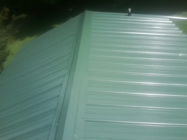 New green metal panels meeting at the ridge of a roof — Flat Roof Repair work by our crew in Lithonia
