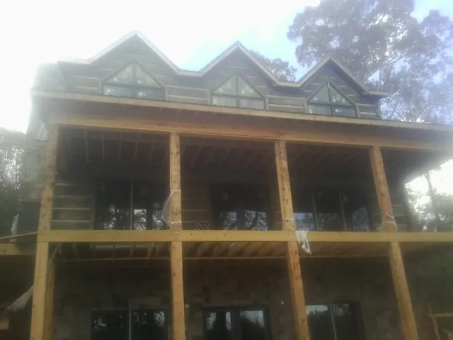 Dormers and porch framing on a large log home under construction — Roof Coating work by our crew in Lithonia