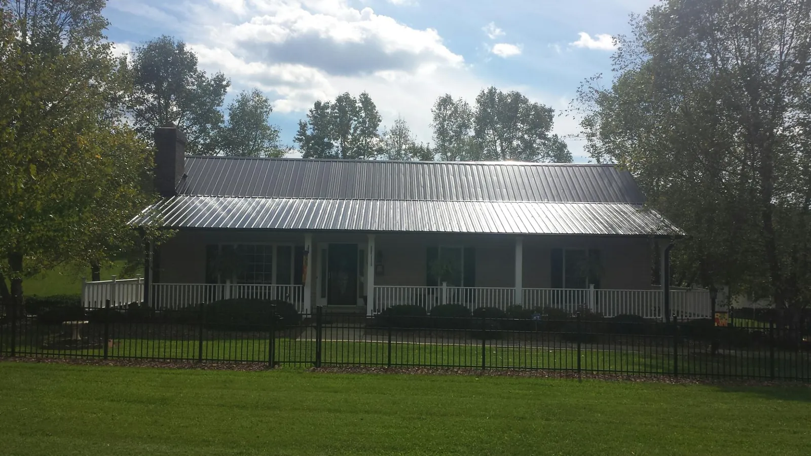 Gray metal roof on a brick ranch with a full width front porch — Gutter Guard Installation work by our crew in Lithonia