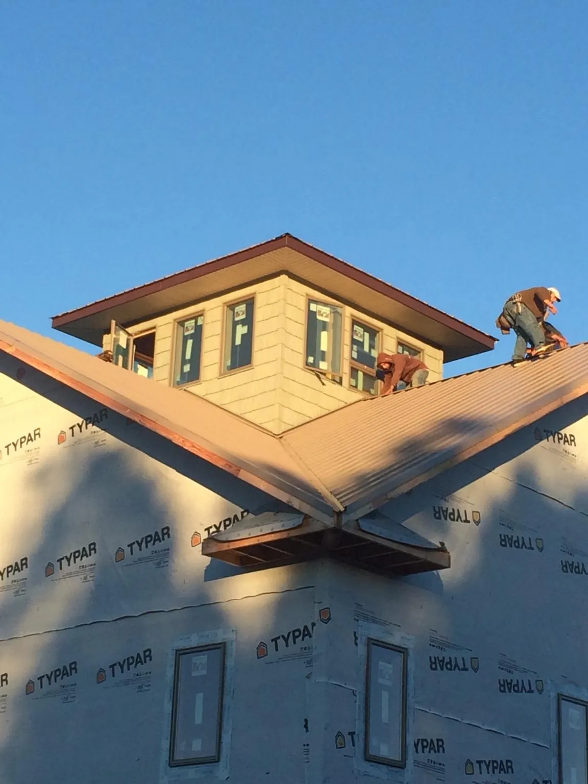 Roofers working around a rooftop cupola on a new metal roof at sunset — Roof Waterproofing in Lithonia by Roofing Brothers